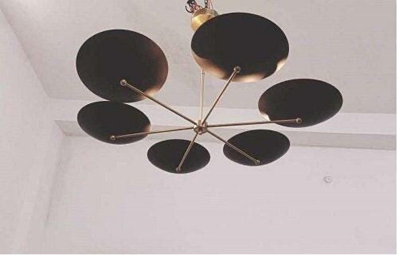 A low-angle shot of the black and brass sputnik chandelier mounted on a white ceiling.