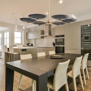 The chandelier installed over a dining table in a modern kitchen and dining room interior.