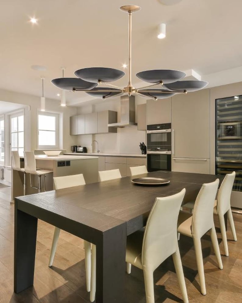 The chandelier installed over a dining table in a modern kitchen and dining room interior.