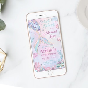 Op de afbeelding: Een smartphone met een digitale uitnodiging voor een eerste verjaardag met zeemeermin-thema. Het ontwerp bevat een pastelkleurige aquarel zeemeermin-staart, schelpen en koraal, met de tekst Splish Splash It's a Mermaid Bash Ariella's 1st Birthday.
