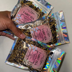 May include: Three silver holographic pouches with a pink and white label that reads "HALEY SELENE Herbal Blends FAIRYTEA INGREDIENTS Chamomile Lavender Rose Petals Glimmer", each pouch contains dried herbs.