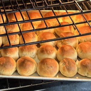 May include: A baking sheet filled with golden brown rolls in an oven. The rolls are arranged in rows and are slightly overlapping.
