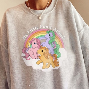 May include: Gray sweatshirt with a graphic of three My Little Pony characters with a rainbow and the text "My Little Panic Attack".
