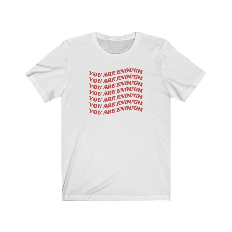 May include: White t-shirt with the phrase "You are enough" repeated in red text.