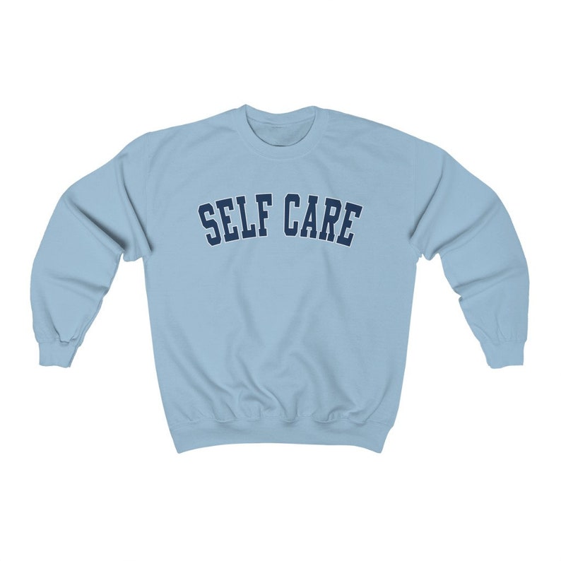 Peut inclure: Un sweat-shirt bleu clair avec le texte "SELF CARE" en bleu marine.