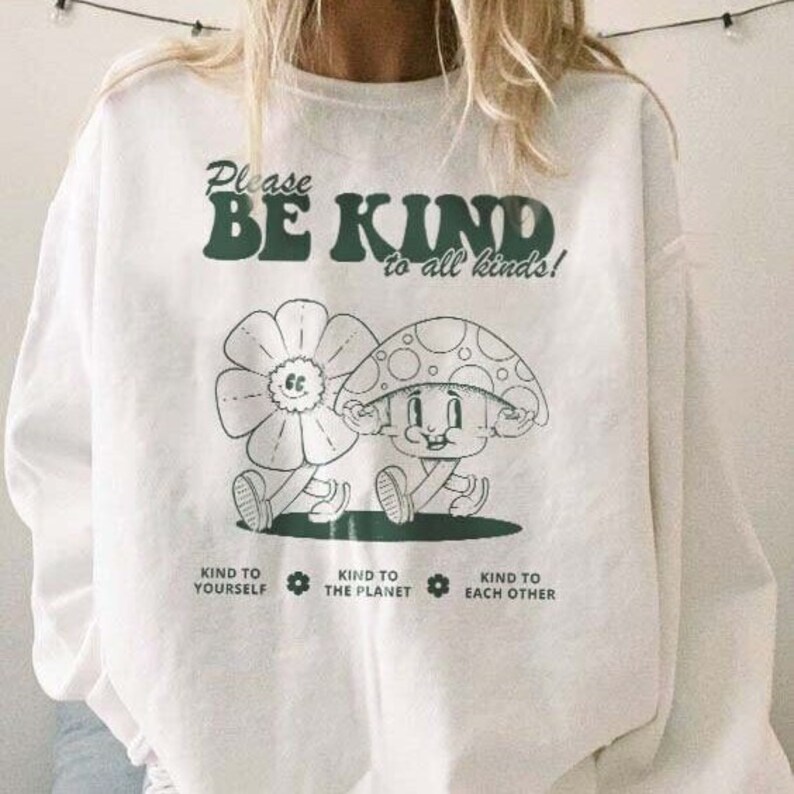 May include: White sweatshirt with a green graphic of a flower and mushroom with the text "Please Be Kind to all kinds!" and "Kind to Yourself, Kind to the Planet, Kind to Each Other" below.