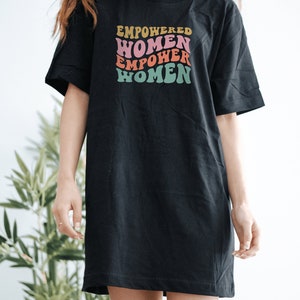 May include: Black oversized t-shirt with a retro-style graphic that reads "EMPOWERED WOMEN EMPOWER WOMEN" in pink, orange, yellow, and green.