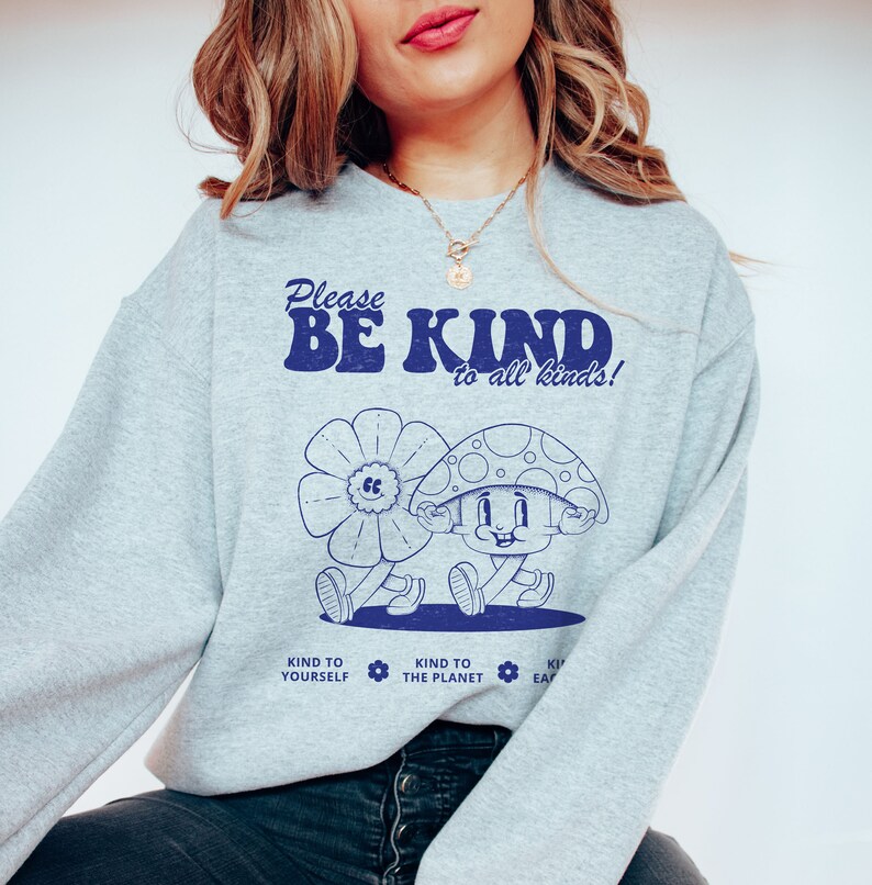May include: Gray sweatshirt with a blue graphic of a mushroom character and the text "Please Be Kind to all kinds!" with three smaller icons below that say "Kind to Yourself", "Kind to the Planet", and "Kind to Each Other".