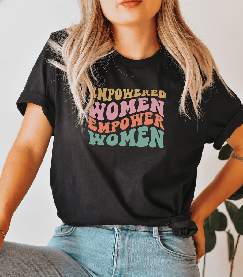 May include: A black t-shirt with a retro-style graphic that says "Empowered Women Empower Women" in rainbow colors.