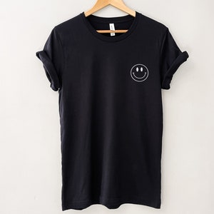 Op de afbeelding: Een zwart T-shirt met een witte smiley-print op de linkerborst.