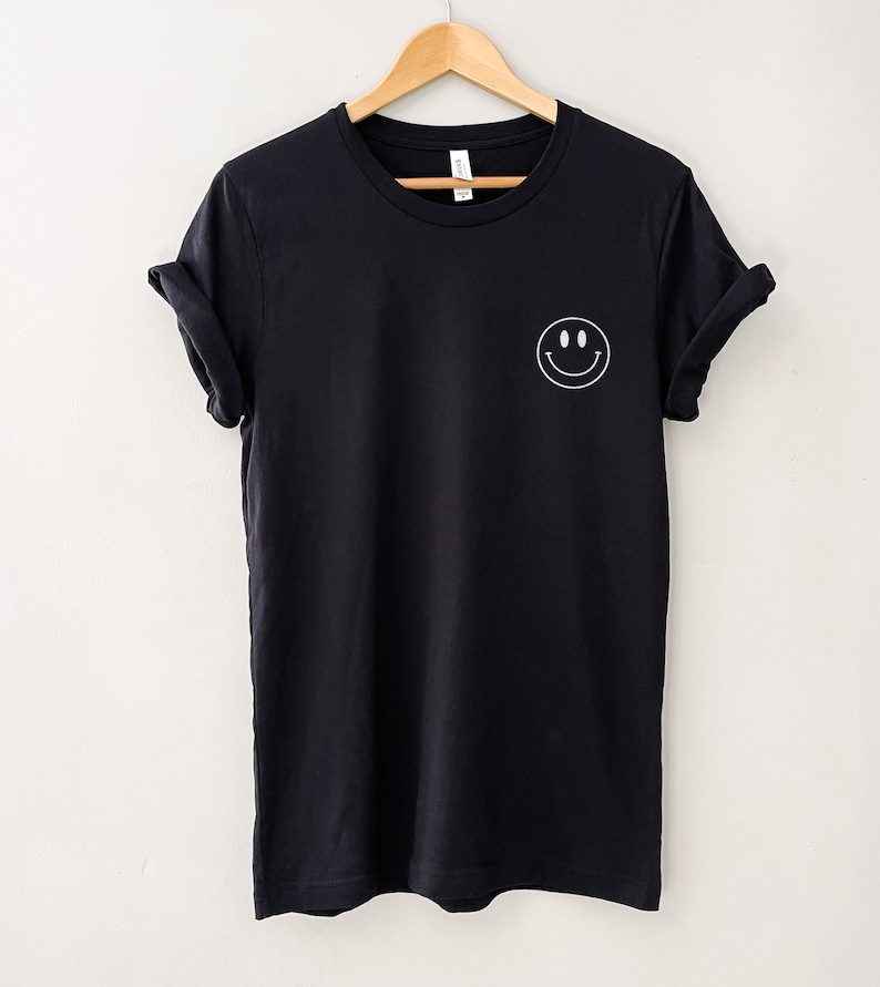 Op de afbeelding: Een zwart T-shirt met een witte smiley-print op de linkerborst.