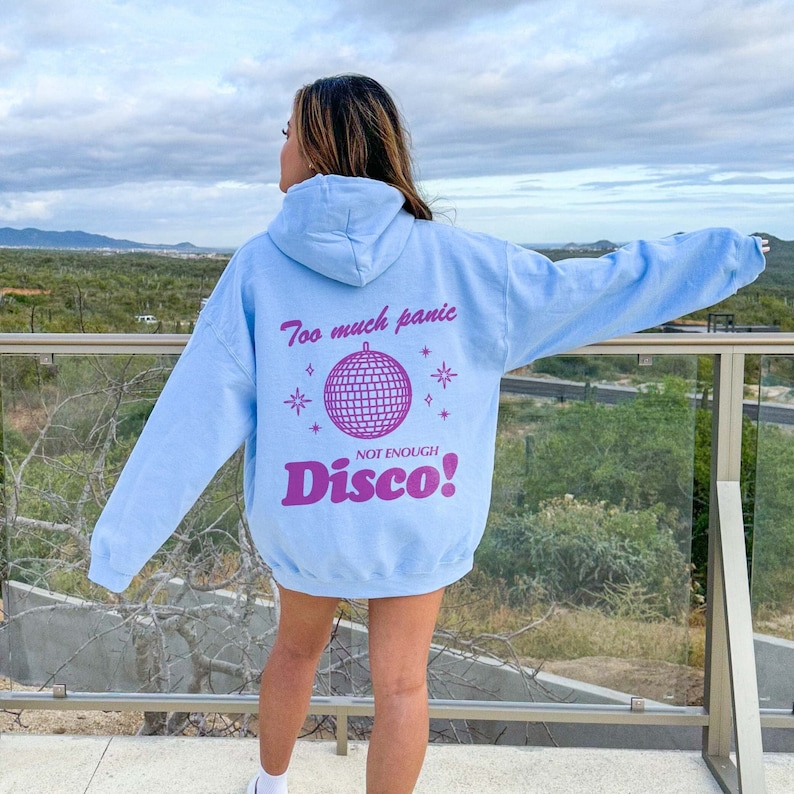May include: A light blue hoodie with a pink graphic of a disco ball and the text "Too much panic, Not enough Disco!"