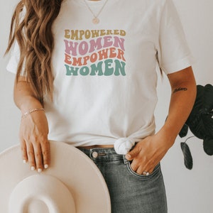 May include: White t-shirt with a retro-style graphic that reads "Empowered Women Empower Women".