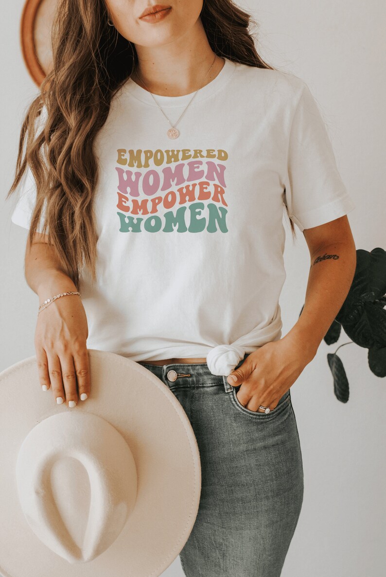 May include: White t-shirt with a retro-style graphic that reads "Empowered Women Empower Women".