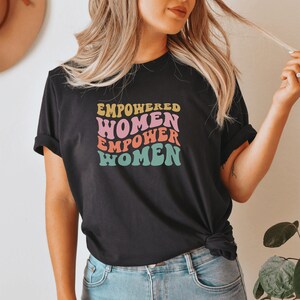 May include: A black t-shirt with a colorful graphic that reads "Empowered Women Empower Women".