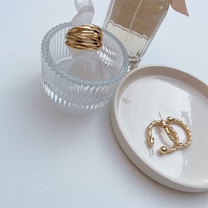 Könnte beinhalten: Zwei Paar goldene Creolen. Ein Paar ist ein schlichtes, gedrehtes Design, das andere ist ein mehrschichtiges Design mit mehreren Bändern.