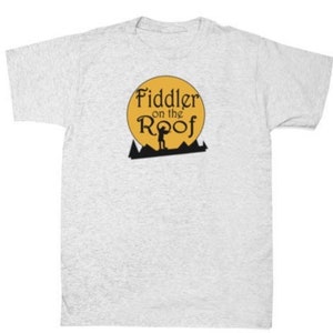 Peut inclure: Un t-shirt gris avec un cercle jaune et le texte "Fiddler on the Roof" en noir. Une silhouette d'une personne jouant du violon est à l'intérieur du cercle.
