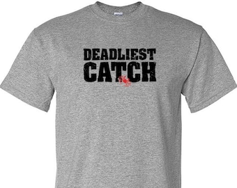 May include: A gray t-shirt with the words "Deadliest Catch" printed in black on the front. A red crab is also visible on the shirt.
