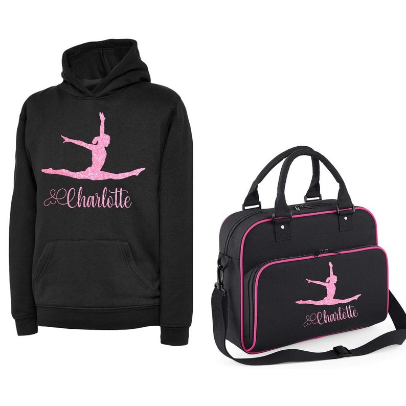 Puede incluir: Sudadera negra con una silueta de gimnasta rosa y el nombre "Charlotte" en purpurina rosa. Una bolsa de deporte negra a juego con ribete rosa y el mismo dise&ntilde;o.