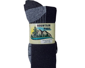 May include: A pair of black and gray merino wool socks with a gray and white stripe pattern. The socks are folded and packaged with a label that reads "Mountain Pass Merino Wool Socks Fits 10-13 Made in USA."