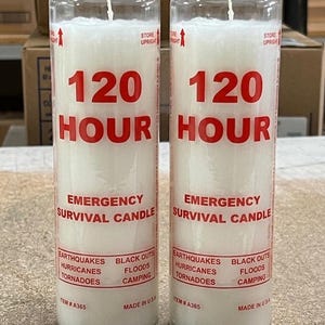 May include: Two clear glass emergency survival candles. Each candle has a white wax interior and a wick. Red text reads "120 HOUR EMERGENCY SURVIVAL CANDLE". The labels list potential emergencies.