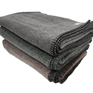 May include: Three gray wool blankets stacked on top of each other. The blankets have black stitching around the edges.