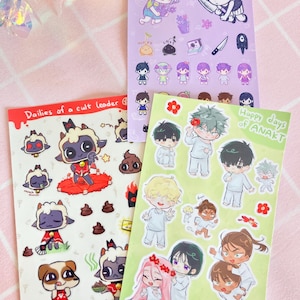 May include: Three sticker sheets featuring characters from the video game Omori. The first sheet features a character with green hair and a flower crown, the second sheet features a character with black hair and a red crown, and the third sheet features a character with green hair and a white shirt.