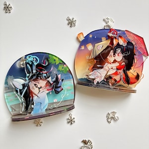 May include: Two semi-circular acrylic display stands featuring anime-style character illustrations. One depicts characters in blue and white robes by a pond, while the other shows characters in red and white outfits with fox ears under a sunset sky.