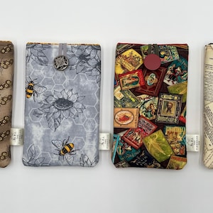 May include: Four fabric phone cases with different patterns. One case has a brown moth pattern, another has a gray bee and sunflower design, a third has a collage of vintage images, and the last has a vintage paper design.