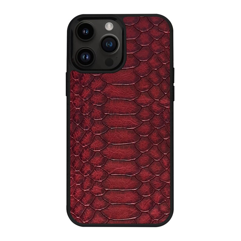 Op de afbeelding: Een smartphonehoesje met een dieprood, gestructureerd slangenleerpatroon op de achterkant. Het hoesje heeft een zwarte rand en een uitsparing voor een camerasysteem met drie lenzen in de linkerbovenhoek, met zicht op de zwarte cameralenzen.