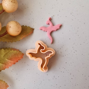 May include: A set of three ceramic mugs with a speckled, matte finish. The mugs are in shades of cream, light gray, and dark gray. Each mug has a simple, minimalist design and a rounded handle. The mugs are stacked on top of each other.