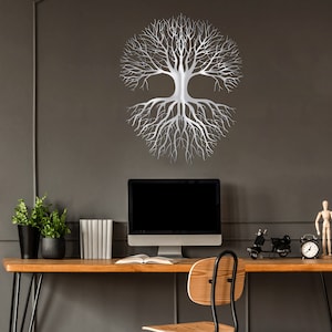 May include: A silver metal tree of life wall art decor. The tree design features a symmetrical arrangement of branches and roots. The artwork is mounted on a dark gray wall above a wooden desk with a computer and other decorative items.
