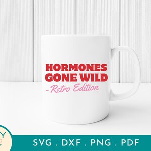 May include: A white ceramic mug with the text "HORMONES GONE WILD - Retro Edition" in red and pink lettering. The mug has a standard handle and is set against a white background.