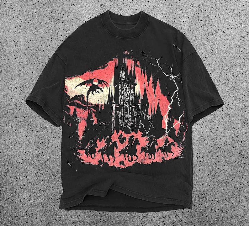 May include: Black t-shirt with a graphic print of a castle, a dragon, and people riding horses. The graphic is in shades of red and black.
