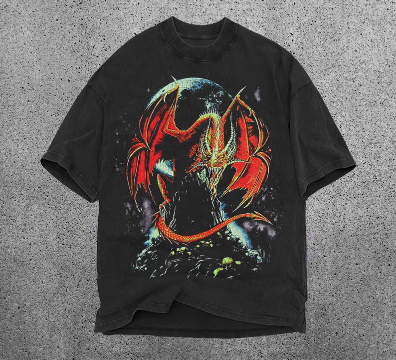 May include: Black t-shirt with a striking graphic of a red and orange dragon with large wings, set against a dark background with a celestial body. The dragon is perched on a rocky surface. The shirt has a classic crew neck.
