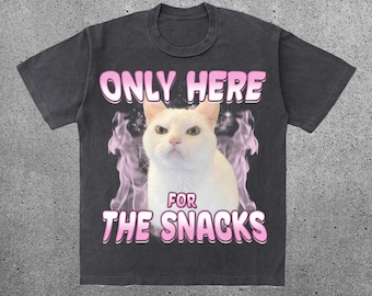 Può includere: Una maglietta nera con un gatto bianco e testo rosa che dice "Only here for the snacks".