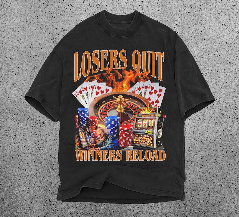 May include: Black t-shirt featuring a graphic of a casino roulette wheel, slot machine, and playing cards. The text "Losers Quit Winners Reload" is printed on the shirt.