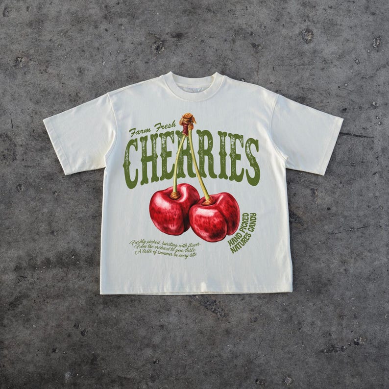 Puede incluir: Una camiseta blanca con un estampado gr&aacute;fico de dos cerezas rojas y el texto "Farm Fresh Cherries Hand Picked Nature's Candy".