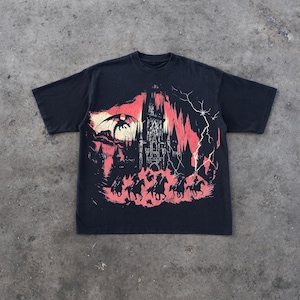 May include: Black t-shirt with a graphic print of a castle, a dragon, and horses in a red and black color scheme.