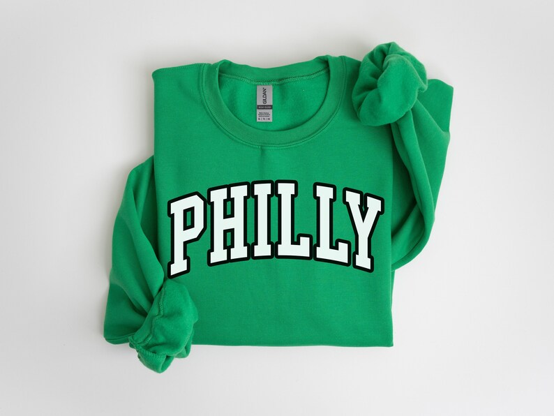 May include: Green sweatshirt with the word "PHILLY" printed in white with a black outline.