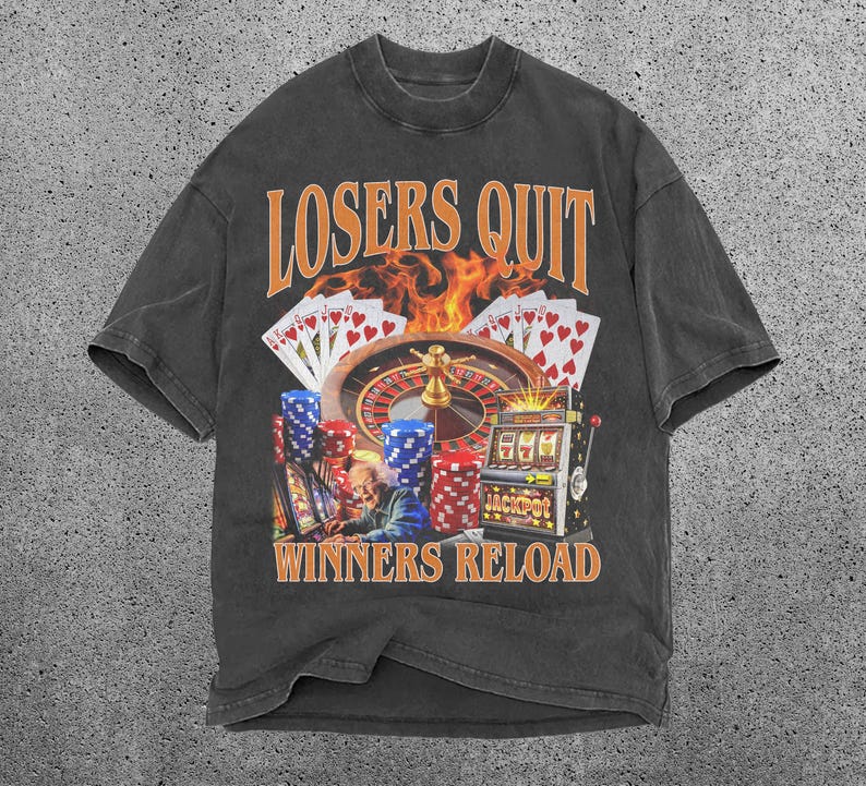 May include: Black t-shirt featuring a graphic print of a casino scene with a roulette wheel, slot machine, and playing cards. The text "Losers Quit Winners Reload" is printed on the shirt.