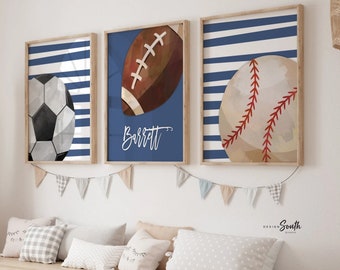May include: Three framed prints with blue and white stripes and watercolour illustrations of a football, American football, and baseball. The middle print has the name "Barrett" written in white.