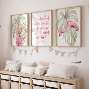 May include: Three framed watercolor prints with botanical and inspirational themes. One features a pink pineapple, another has the quote "Be who God created you to be & you will set the world on fire", and the last shows pink flamingos. The prints are displayed above a storage bench.