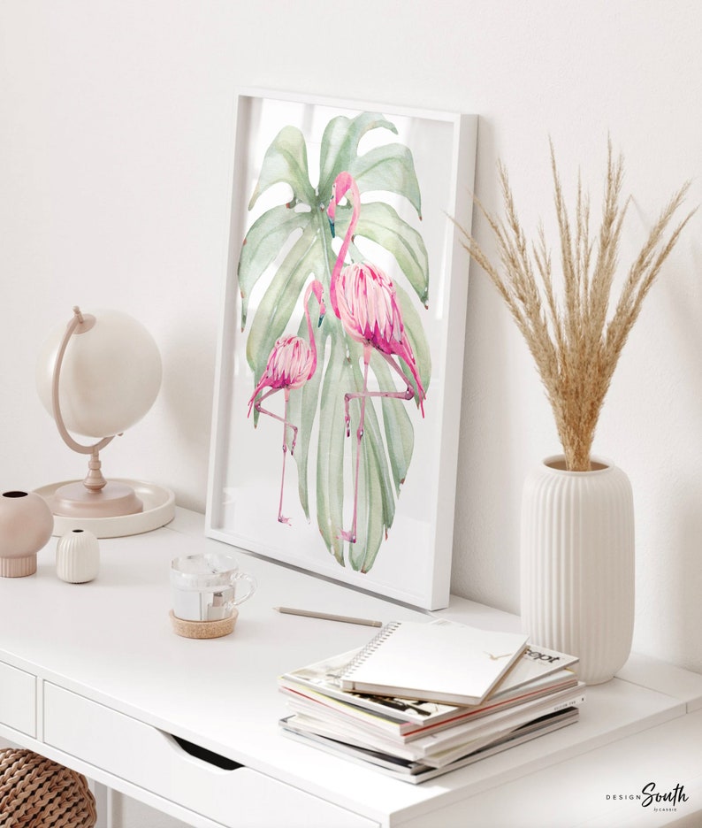 May include: Three framed prints with a tropical theme. The prints feature pink flamingos, green monstera leaves, and a pink pineapple. The center print has a pink quote that reads 'Be who God created you to be & you will set the world on fire.' The quote is attributed to St. Catherine of Siena.