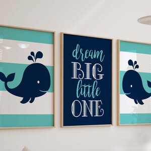 Könnte beinhalten: Drei gerahmte Drucke mit nautischem Thema. Der mittlere Druck hat einen dunkelblauen Hintergrund mit weißem Text, der "dream big little one" lautet. Die Drucke auf beiden Seiten haben einen weißen und türkisfarbenen gestreiften Hintergrund mit einer dunkelblauen Wal-Silhouette.
