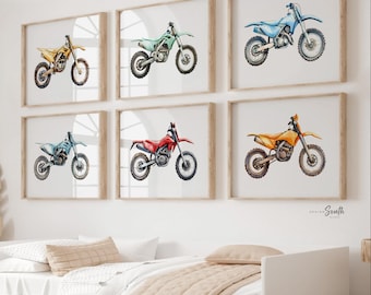 May include: Six framed watercolor prints of dirt bikes in various colors: yellow, green, blue, red, and orange. Each motorcycle is depicted in a side profile against a white background, with a wooden frame.