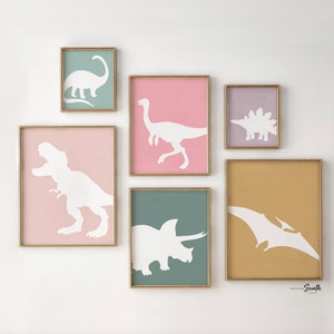 Adorable dinosaur art prints designed for a little girls room, featuring playful dinosaurs in shades of pink, teal, and purple. These vibrant and fun dinosaur illustrations are perfect for adding a touch of adventure and charm to toddler wall decor. Ideal for a girl's nursery, bedroom, or playroom, these art prints create a whimsical and colorful space. Perfect for girls who love dinosaurs, this wall decor adds personality and joy to any room setting, making it a delightful addition to her space