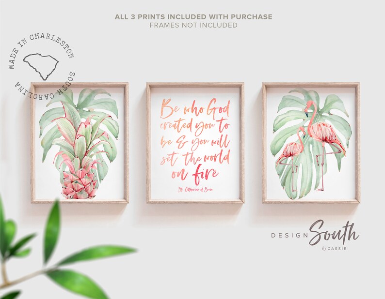 May include: Three framed watercolor prints. The left print features a pineapple with tropical leaves. The center print has the text "Be who God created you to be & you will set the world on fire." The right print shows two flamingos. The prints are in wooden frames.