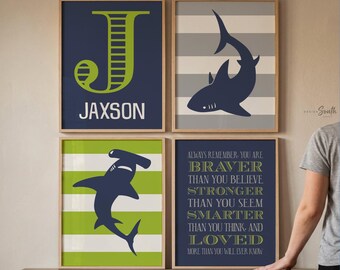 May include: A set of four framed wall art prints. One features a lime green letter J and the name JAXSON on a navy background. Another shows a navy shark on grey stripes. A third displays a navy hammerhead shark on lime green stripes. The fourth has text.