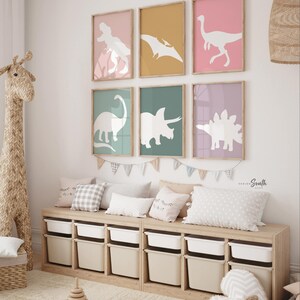 Adorable dinosaur art prints designed for a little girls room, featuring playful dinosaurs in shades of pink, teal, and purple. These vibrant and fun dinosaur illustrations are perfect for adding a touch of adventure and charm to toddler wall decor. Ideal for a girl's nursery, bedroom, or playroom, these art prints create a whimsical and colorful space. Perfect for girls who love dinosaurs, this wall decor adds personality and joy to any room setting, making it a delightful addition to her space